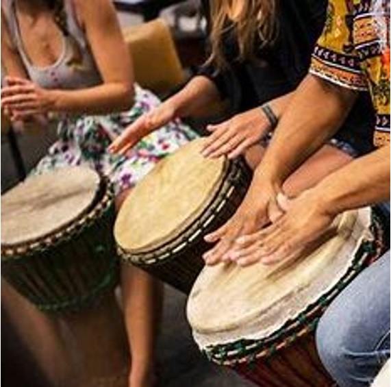 Three drums are pictured at an angle with hands above them, caught actively drumming